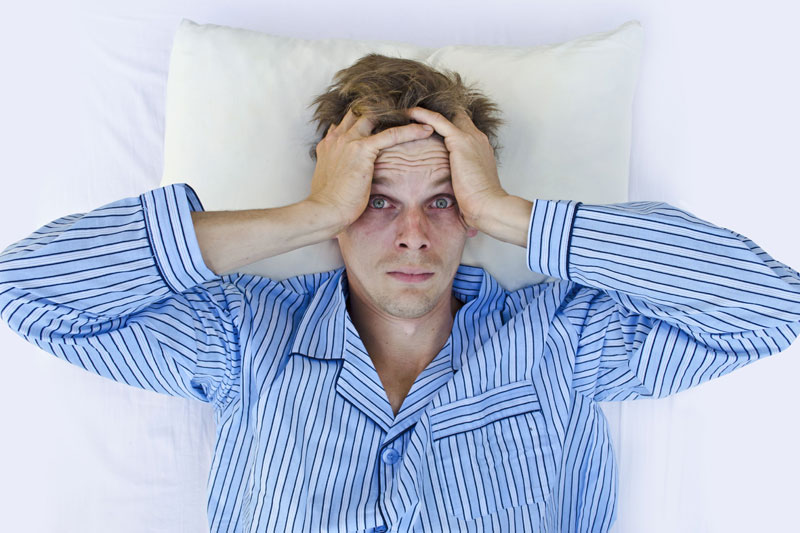 Man holding head in bed | Comprehensive Sleep Services | Dallas | Fort Worth | Sleep Apnea Treatment